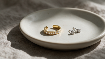 Diamond ear cuff and platinum studs on a bone-white ceramic dish