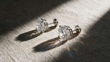 Two diamond studs under directional light, one fanning into a faint spectrum