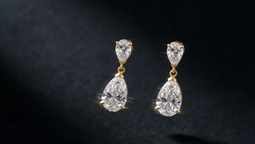 Duet pear-cut diamond drop earrings hanging free against a dark background