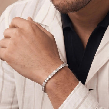 Man wearing a silver bracelet on his wrist, dressed in a white shirt and black shirt.