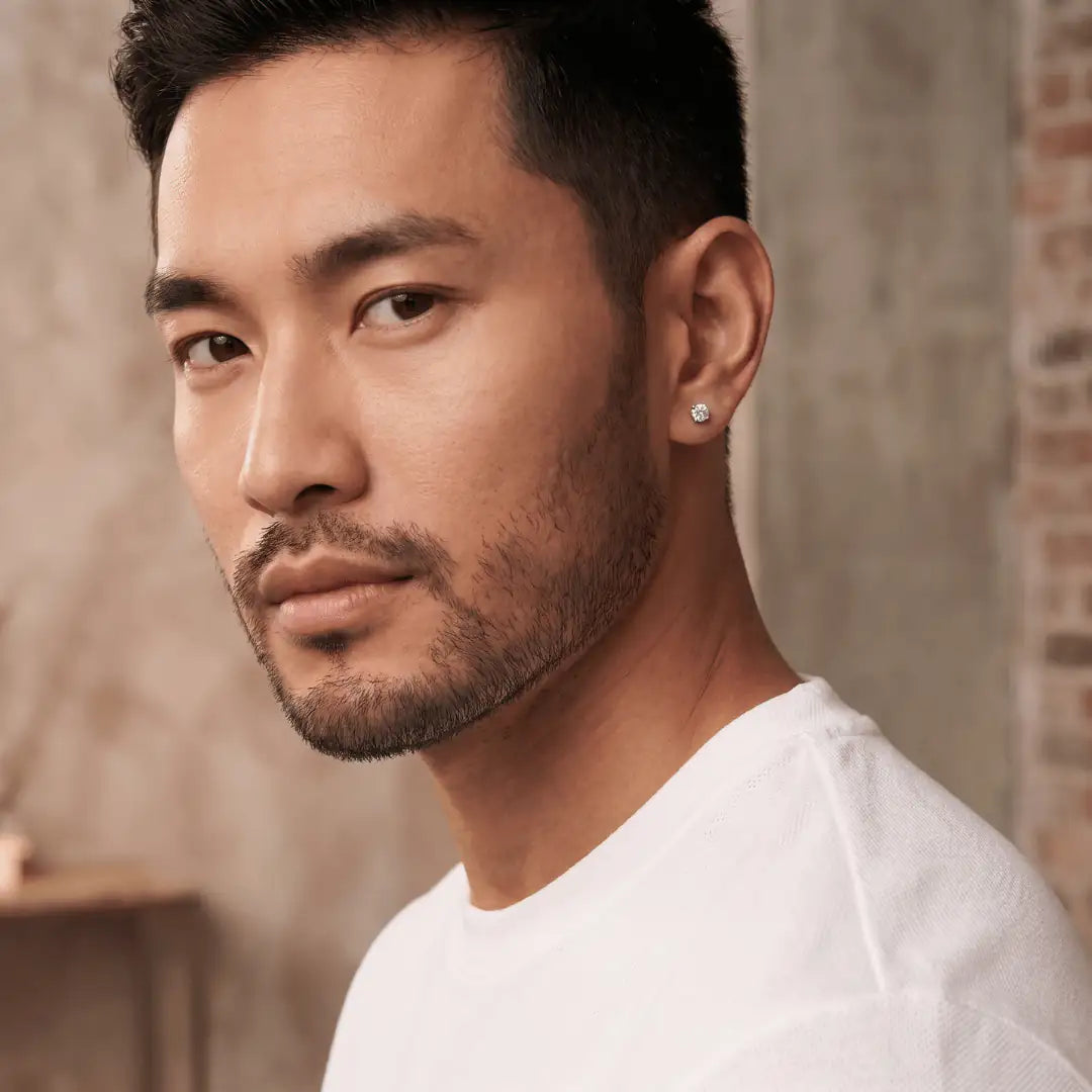 Man wearing a diamond earring against a neutral background