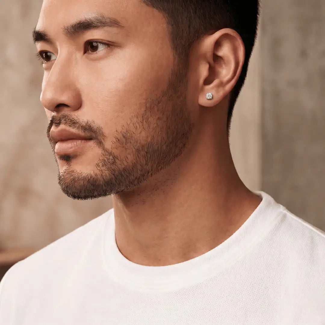 Close-up of a man wearing a diamond earring with a neutral background