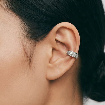 Close-up of an ear wearing a diamond earring with a blurred background