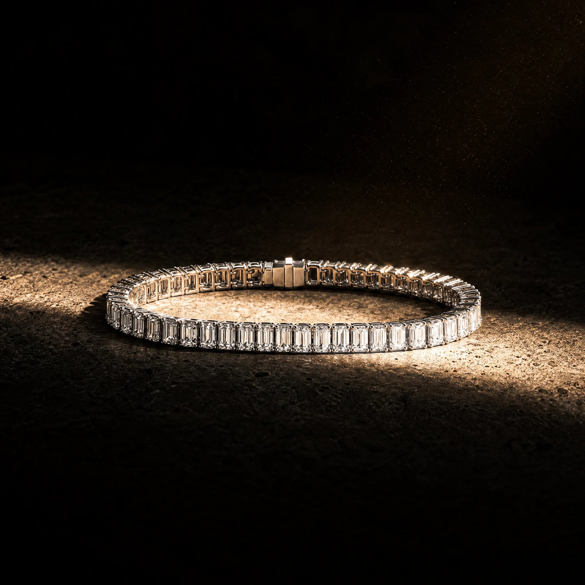 Meridian men's emerald-cut tennis bracelet coiled under warm light, Carat Club Co.